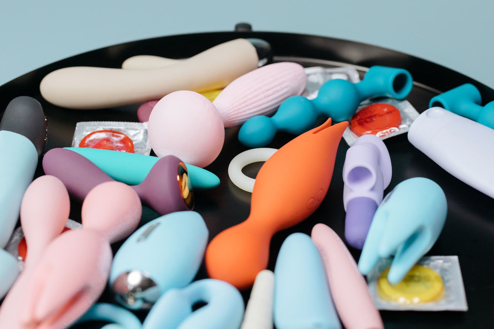 Hand die een oranje vibrator vasthoudt tegen een minimalistische paarse achtergrond