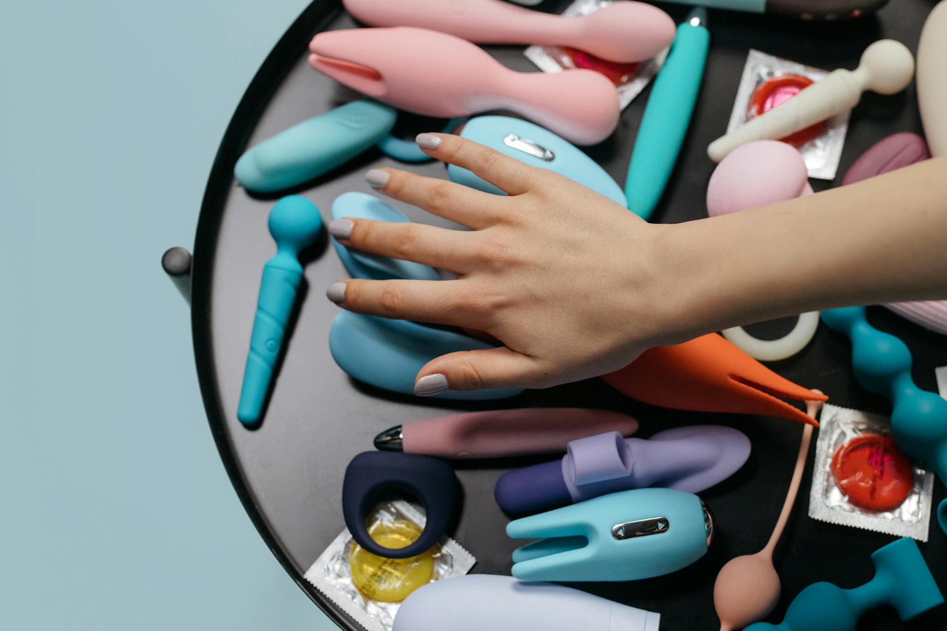 Close-up van een hand die een oranje vibrator vasthoudt tegen een minimalistische paarse achtergrond
