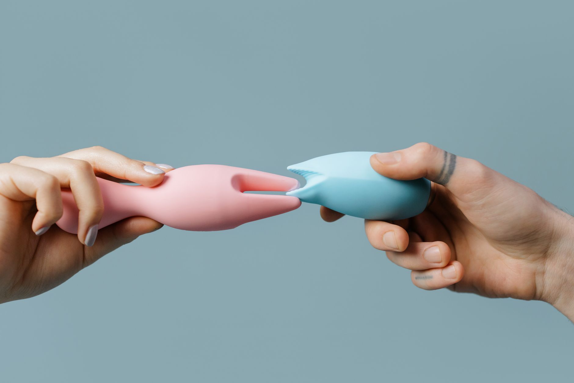 Handen houden een elegante blauwe vibrator tegen paarse achtergrond