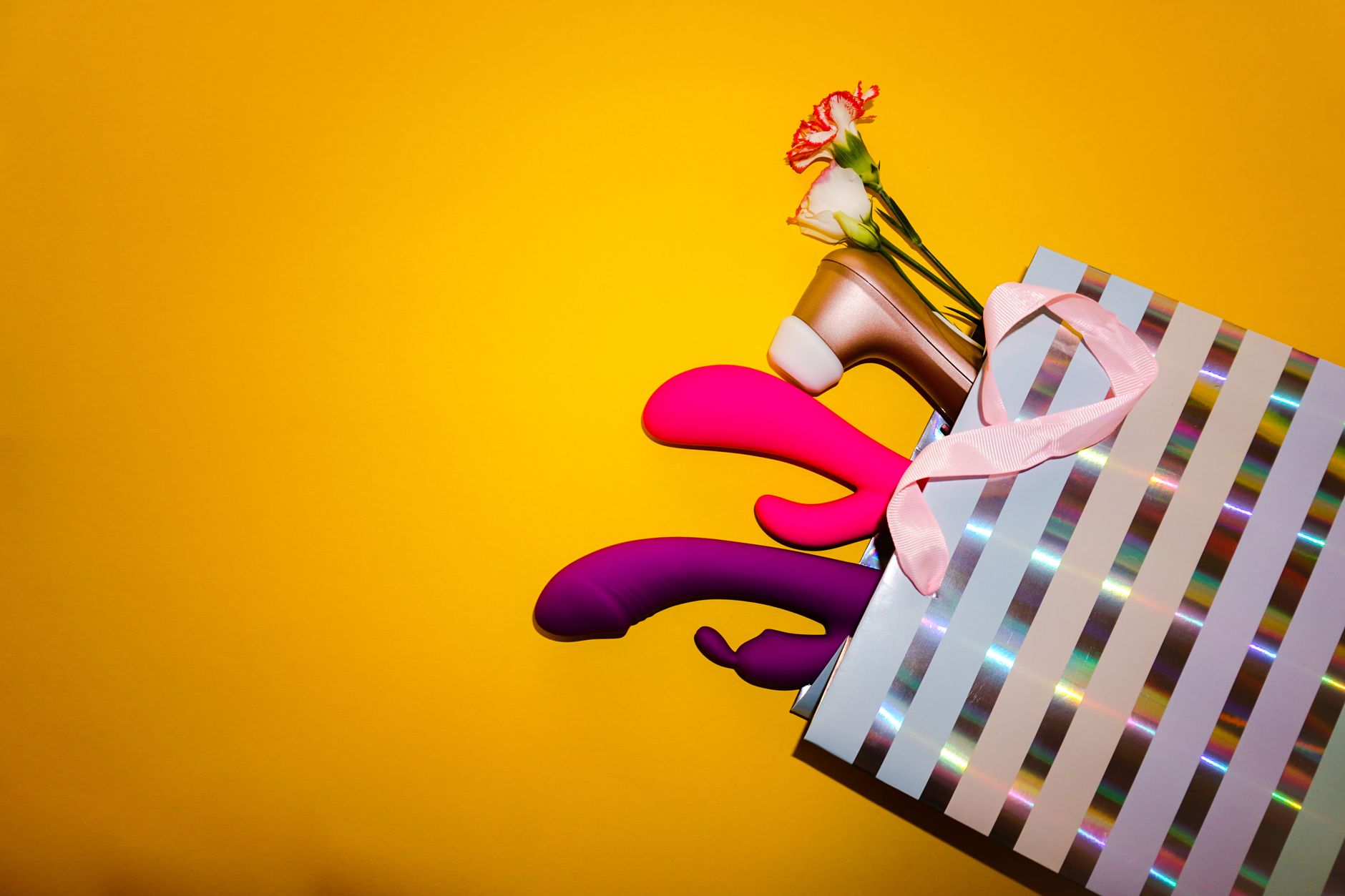 Vrouw houdt blauwe en roze siliconen vibrators vast en kijkt nadenkend naar beneden